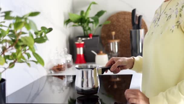 一个年轻的女人在一个现代化的厨房里用一个镀铜的土耳其咖啡壶煮咖啡 早餐咖啡的概念 慢动作在家煮咖啡的过程 — 图库视频影像