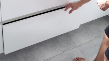 Genç bir adam mutfaktaki konteynırlarda çöpleri ayırıyor. Atık ayıklama sistemi olan modern bir mutfak. Atık Ayrım Konsepti. Sıfır kayıp. Çevre dostu. 4K görüntü.