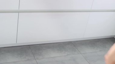 A young woman sorts garbage in containers in the kitchen. Modern kitchen with a system for sorting waste. Waste Separation Concept. Zero waste. Eco-friendly. 4K footage.