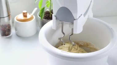 Karıştırıcı hamuru çevirme kabında karıştırıyor. Kaseli sabit bir mikser hamuru ağır çekimde yoğurur..