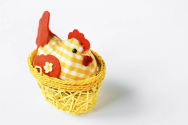 Decorative chicken in a yellow wicker basket on a white isolated background with space for text. Easter card Provence. Easter composition.