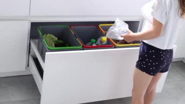 A small child sorts garbage in containers in the kitchen in slow motion. Modern kitchen with a system for sorting waste. Waste Separation Concept. Zero waste. Eco-friendly.