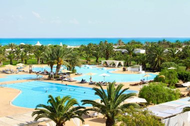 Denizin ilk sahil şeridindeki otel kompleksinin üst manzarası. Havuzu ve dinlenmek için güzel yeşil bir alan. Turizm, tatil ve dinlenme konsepti.