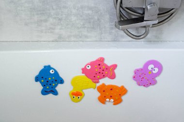 Çocukların renkli balık şeklinde yüzme oyuncakları banyoda asılı duruyor. Çocuk bakımı. Bir çocuğu yıkıyorum. Çocuk hijyeni. Bir çocukla akşam ayini..