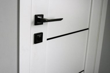 Modern beyaz iç kapının yeni, şık metal kapı tokmağının yakın çekimi. İçsel detaylar kavramı. Doğramacılık. Kapı kilidi. Kapı montajı. Minimalizm tarzında modern iç mimari.