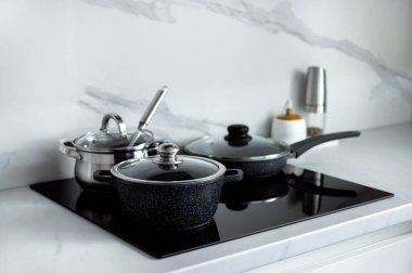 Tencereler elektrikli sobanın üzerinde duruyor. Minimalizm tarzında modern mutfak. Mutfağın içi..