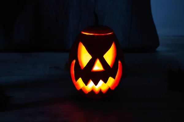 Halloween\'s holiday attributes. Lantern carved from pumpkin known as Jack-o-lantern glow in the dark on a black background with spider webs, autumn leaves and balloons. Trick or treat.