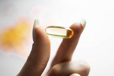 Genç kadın elleri sarı omega-3 jel kapsülünü yakından tutuyor. Balık yağı takviyesi. Sağlık, vitamin ve ilaç kavramı. Omega 3 balık yağı kapsülleri, E vitamini..
