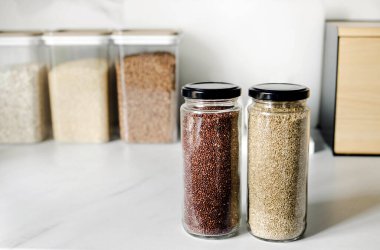 Modern bir mutfağın arka planında kırmızı ve beyaz kinoalar. Sağlıklı gıda ve beslenme konsepti. Güvenli, ekolojik ve sağlıklı ürünler. Çevresel ambalaj, haşere kontrolü.