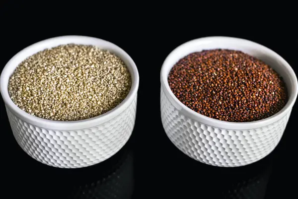 Röd Och Vit Quinoa Två Vita Plattorna Den Svarta Bakgrunden — Stockfoto