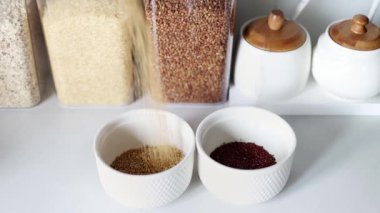 Kırmızı ve beyaz kinoalar modern bir mutfağın arka planına karşı ağır çekimde beyaz bir tabağa dökülür. Sağlıklı gıda ve beslenme konsepti. Güvenli, ekolojik ve sağlıklı ürünler.