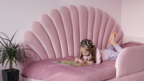 Küçük Bir Kız Kitabın Yanında Yatıyordu Cep Telefonu Kullanıyordu Bir — Stok video
