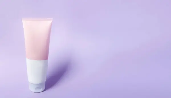 A clean label facial or body cream tube is isolated on a violet background. Beauty product mockup. Wellness packaging. Banner for Branding. Cream bottle, lotion, mousse, cleanser, shampoo for skincare routine. Copy space.