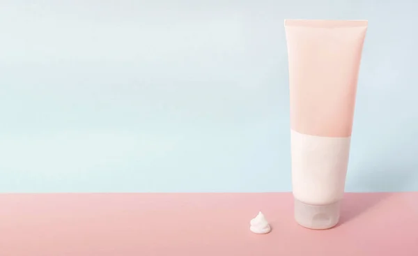 Clean label facial or body cream tube and product squeezed cream texture is isolated on a pink background. Beauty product mockup. Wellness packaging. Banner for Branding. Cream bottle, lotion, mousse, cleanser, shampoo for skincare routine. Copy spac