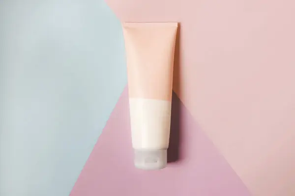 A clean label facial or body cream tube is isolated on a multi-color background. Beauty product mockup. Wellness packaging. Branding spa. Cream bottle, lotion, mousse, cleanser, shampoo for skincare routine. Copy space.