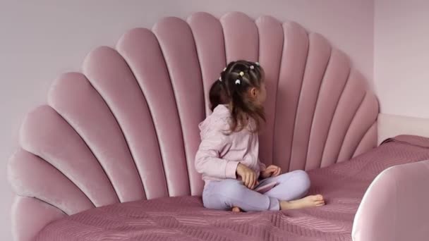 Avrupalı Görünümlü Küçük Bir Kız Yatakta Oturmuş Telefonda Müzik Eşliğinde — Stok video