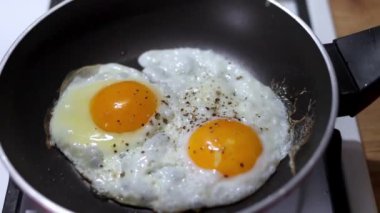 İki tavuk yumurtası yavaş çekimde bir tavada kızartılır. Kahvaltı konsepti.