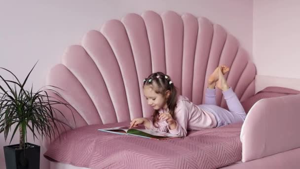Ένα Κοριτσάκι Είναι Ξαπλωμένο Στο Κρεβάτι Κοιτάζοντας Βιβλίο Αργή Κίνηση — Αρχείο Βίντεο