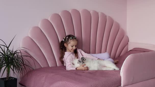 Mała Dziewczynka Europejskim Wyglądzie Przytulająca Małego Białego Szwajcarskiego Szczeniaka Łóżku — Wideo stockowe