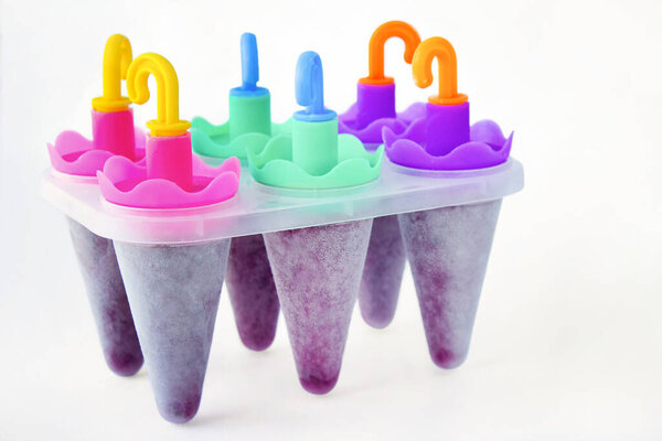 Домашнее фруктовое мороженое с ягодами в плесени изолированы на белом фоне. Летняя еда: приготовление домашнего фруктового льда. Шесть розовых форм мороженого.