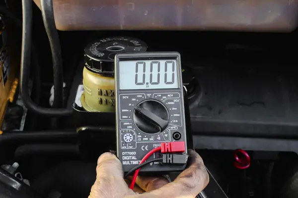Checking voltage with multimeter. Recovery of acid batteries, resuscitate car battery. Voltmeter to check voltage level on car battery. Car service station. Car repair.