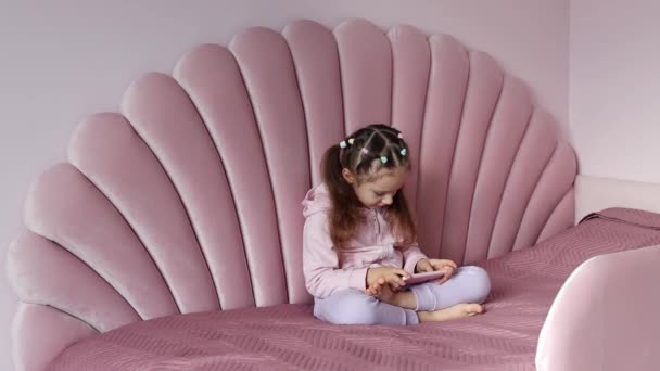 Ένα Κοριτσάκι Ευρωπαϊκής Εμφάνισης Κάθεται Στο Κρεβάτι Και Χρησιμοποιεί Ένα — Αρχείο Βίντεο