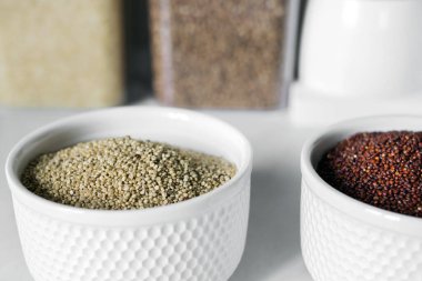 Modern bir mutfağın arka planındaki iki beyaz tabakta kırmızı ve beyaz kinoa. Sağlıklı gıda ve beslenme konsepti. Güvenli, ekolojik ve sağlıklı ürünler.