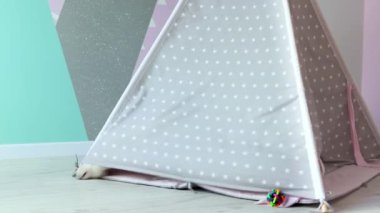 Beyaz İsviçreli bir köpek yavrusu çocuk odasında yaramazca oynuyor. Bir çocuk çadırında sevimli beyaz bir köpek yavrusu oynuyor. Evcil hayvan konsepti. 4k görüntü.