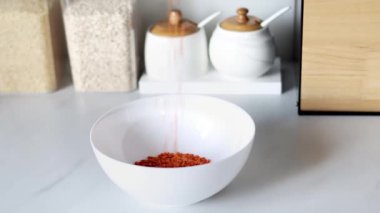 Kırmızı mercimek, modern bir mutfağın arka planına karşı ağır çekimde beyaz bir tabağa dökülür. Sağlıklı gıda ve beslenme konsepti. Güvenli, ekolojik ve sağlıklı ürünler..
