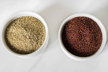 Beyaz arka plandaki iki beyaz tabakta kırmızı ve beyaz kinoa. Sağlıklı gıda ve beslenme konsepti. Güvenli, ekolojik ve sağlıklı ürünler.