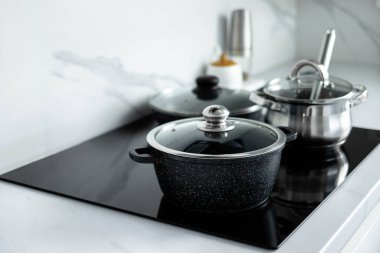 Tencereler elektrikli sobanın üzerinde duruyor. Minimalizm tarzında modern mutfak. Mutfağın içi..