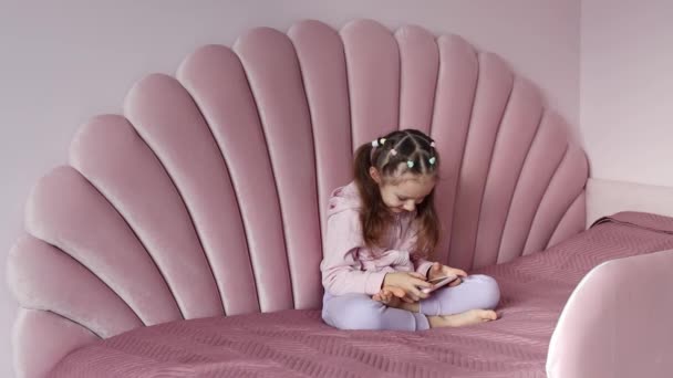 Avrupalı Görünümlü Küçük Bir Kız Yatakta Oturuyor Cep Telefonunu Yavaş — Stok video