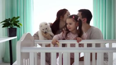 İki çocuklu mutlu bir aile ve küçük beyaz bir köpek yavrusu. Mutlu aile kavramı. Ailedeki evcil hayvan kavramı. Yavaş çekim.