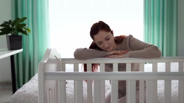 Zmęczona Młoda Matka Zasnęła Opierając Się Łóżeczko Którym Leży Noworodek — Wideo stockowe
