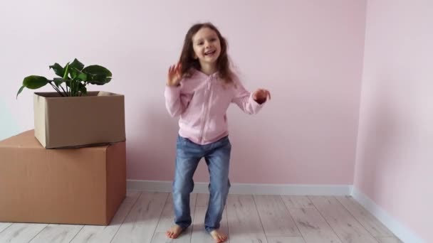 小さな女の子は喜んで箱の近くで物事と踊り 新しい家で喜びました 新しい住宅 不動産 テナンシー ローン 住宅ローン 移転デーコンセプト スローモーション — ストック動画