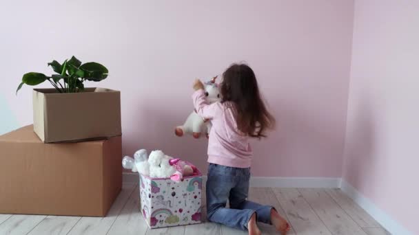 小さな女の子は新しい家に新しい部屋の箱からおもちゃを取り出します 小さな女の子が新しい部屋に引っ越すのを喜んでいる 新しい住宅 不動産 住宅ローン 移転日 — ストック動画