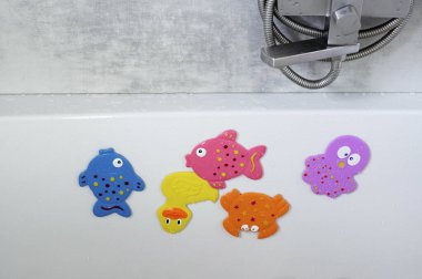 Çocukların renkli balık şeklinde yüzme oyuncakları banyoda asılı duruyor. Çocuk bakımı. Bir çocuğu yıkıyorum. Çocuk hijyeni. Bir çocukla akşam ayini..