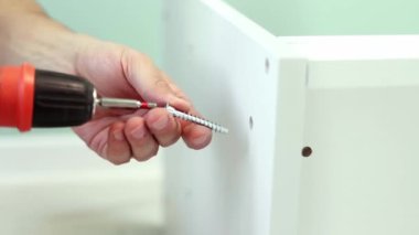 Genç bir zanaatkar mobilya montajı yapıyor. Teyidi yakın plan çekiyoruz. Profesyonel mobilya montajı. Yeni mobilya montajı. Mobilya montajı. 4k görüntü.