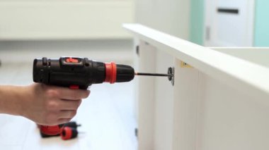 Genç bir zanaatkar mobilya montajı yapıyor. Teyidi yakın plan çekiyoruz. Profesyonel mobilya montajı. Yeni mobilya montajı. Mobilya montajı. 4k görüntü.