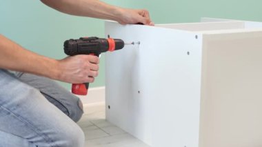 Genç bir zanaatkar mobilya montajı yapıyor. Teyidi yakın plan çekiyoruz. Profesyonel mobilya montajı. Yeni mobilya montajı. Mobilya montajı. 4k görüntü.