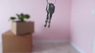 Kutuların arkasındaki eşyalarla birlikte yeni evin anahtarlarını yakın plan çek. Yeni ev. Gayrimenkul, kiracılık, kredi ve ipotek konsepti. Yavaş çekim.