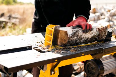 Erkek ellerinin hidrolik odun kırıcıyla huş ağacı yakacak odun kesmesi. Bıçkıhane. Şömine için huş ağacı yakacak..
