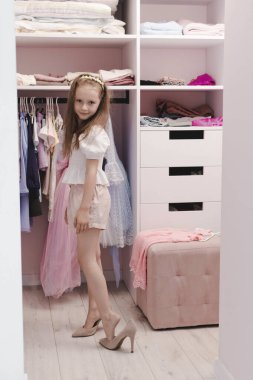 Avrupalı görünümlü küçük bir kız soyunma odasında annesinin ayakkabılarını deniyor. Biraz moda düşkünü. Moda ve tarz kavramı