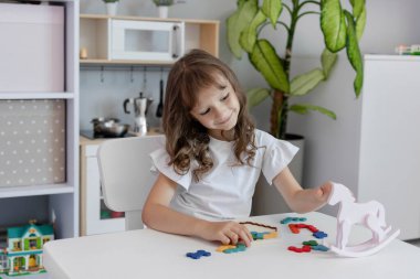 Küçük kız çocuk odasındaki masada masa eğitimi üzerine oyun oynuyordu. Çocuk gelişimi kavramı. Çocuklar için boş zaman kavramı..