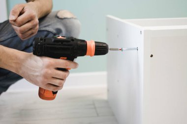 Genç bir zanaatkar mobilya montajı yapıyor. Teyidi yakın plan çekiyoruz. Profesyonel mobilya montajı. Yeni mobilya montajı. Mobilya kurulumu.