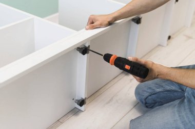 Genç bir zanaatkar mobilya montajı yapıyor. Teyidi yakın plan çekiyoruz. Profesyonel mobilya montajı. Yeni mobilya montajı. Mobilya kurulumu.