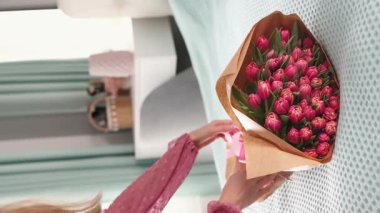 Kadınların elleri tuvalet masasına vazo dolusu lale koyuyor. Bahar Varışı. Sevdiğin biri için buket. Özel etkinlikler. 4K dikey görüntü.