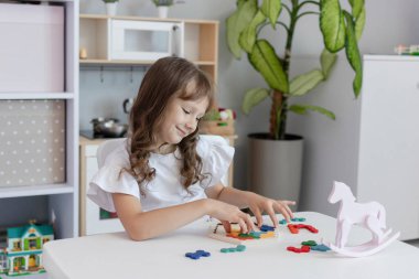Küçük kız çocuk odasındaki masada masa eğitimi üzerine oyun oynuyordu. Çocuk gelişimi kavramı. Çocuklar için boş zaman kavramı..