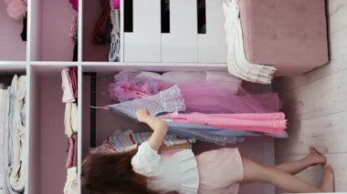 Küçük bir kız eşyalarını yavaş çekimde soyunma odasına asıyor. Biraz moda düşkünü. Moda ve tarz kavramı