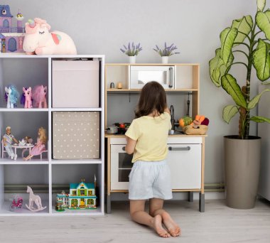 Bir çocuk oyuncak mutfağıyla oynuyor. Çocuk odasında küçük bir kız oynuyor. Çocuklar için boş zaman kavramı..